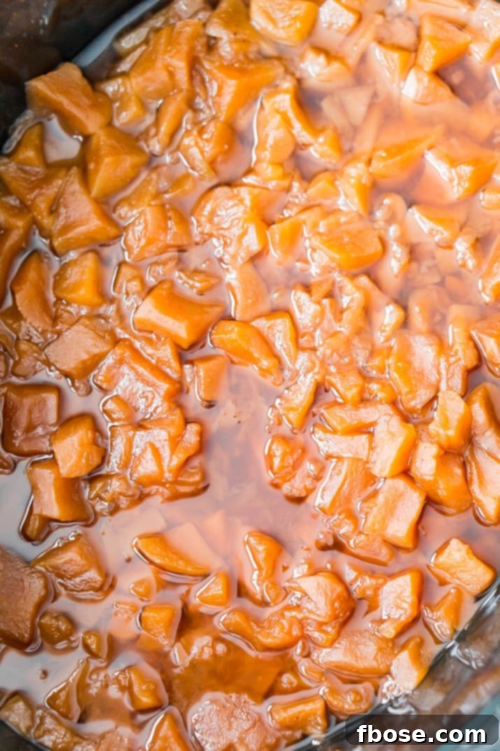 Apples, sugar, and spices simmering in a crockpot, covered for the initial 8-hour slow cook.