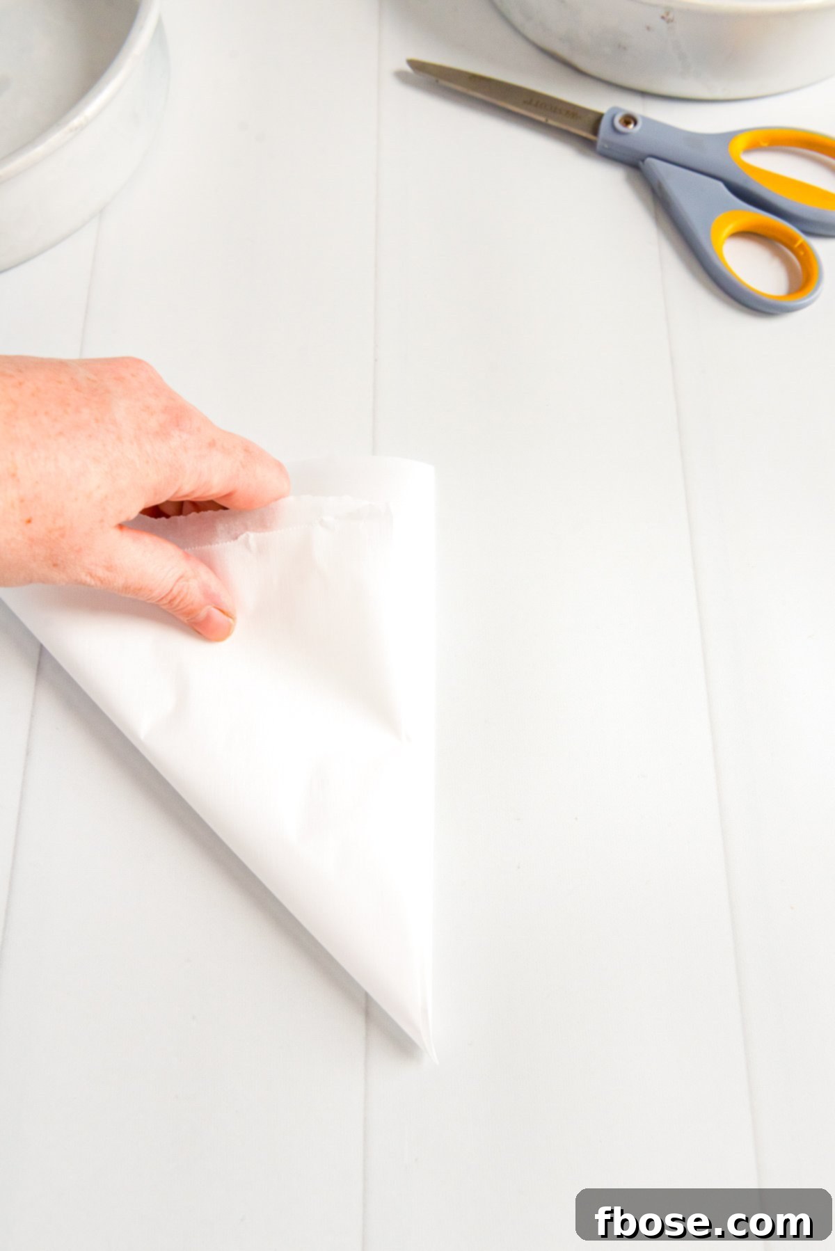 Parchment paper folded into a triangle, showing the precise corner for cutting.