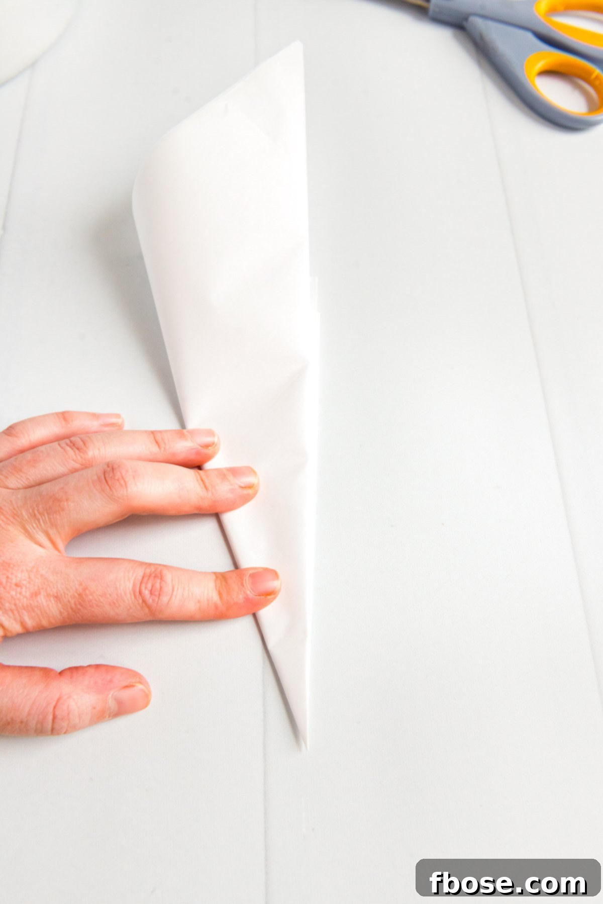 Parchment paper folded into a small, neat triangle for accurate cutting.