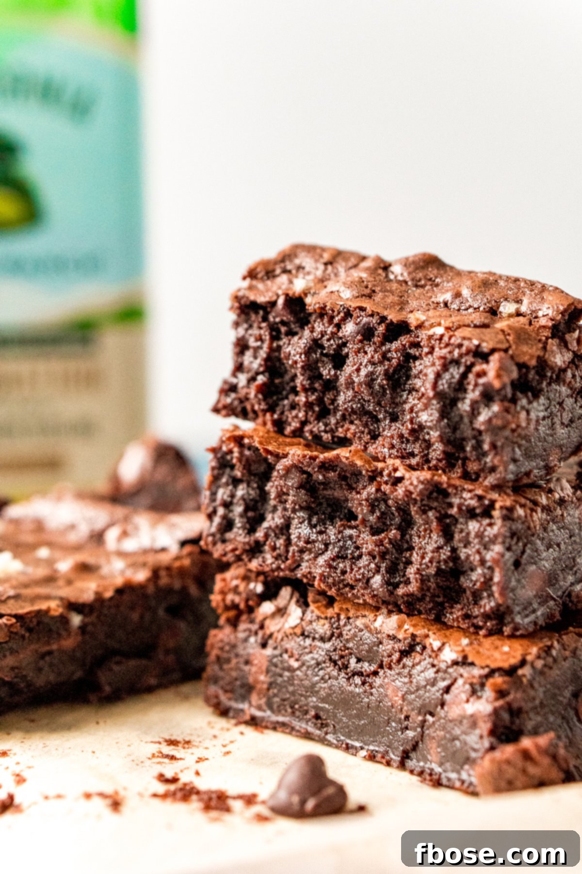 Fudgy Olive Oil Delights 4 A stack of three decadent Olive Oil Brownies, with a bottle of extra virgin olive oil in the background.