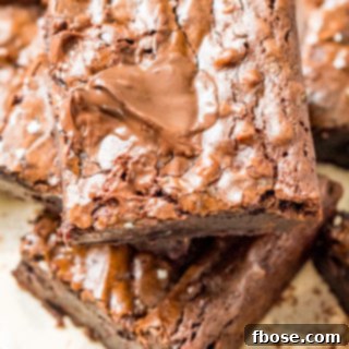 Fudgy Olive Oil Delights 6 Brownie squares stacked on top of each other on parchment paper.