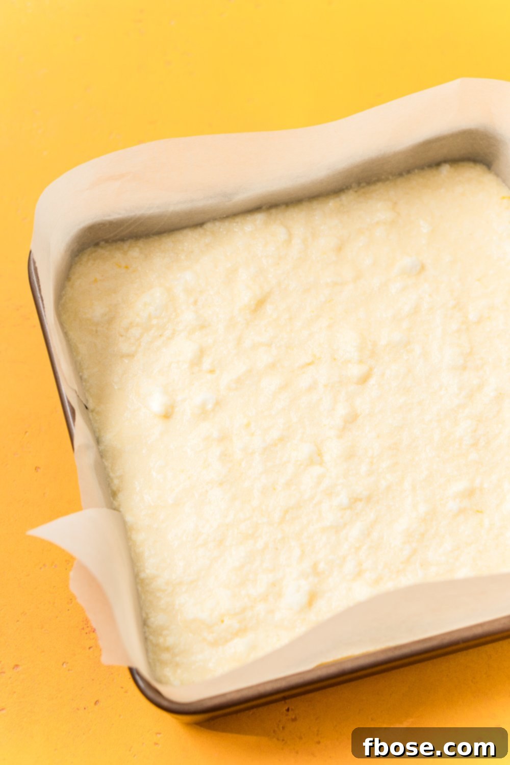Lemon Magic Cake batter poured into a prepared 8x8-inch baking pan.