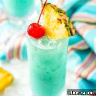 Azure Aloha 6 Angled close up photo of a blue hawaiian cocktail garnished with a pineapple edge and cherry.