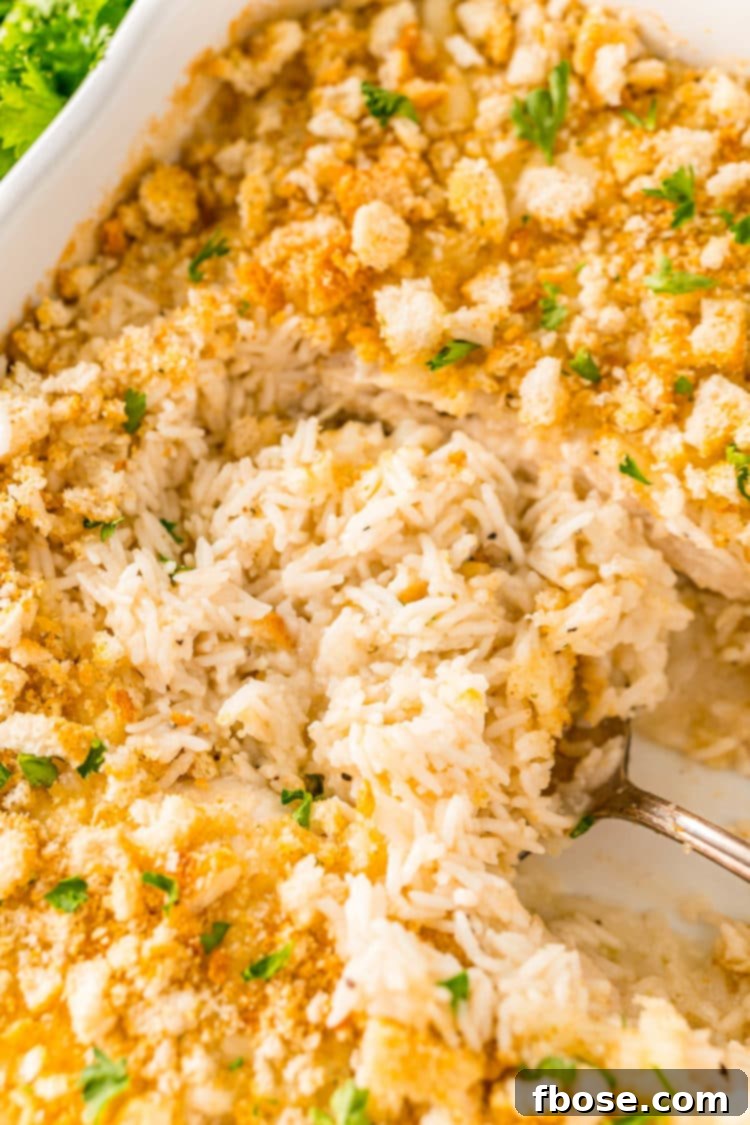 Rice being spooned out of a white casserole dish.