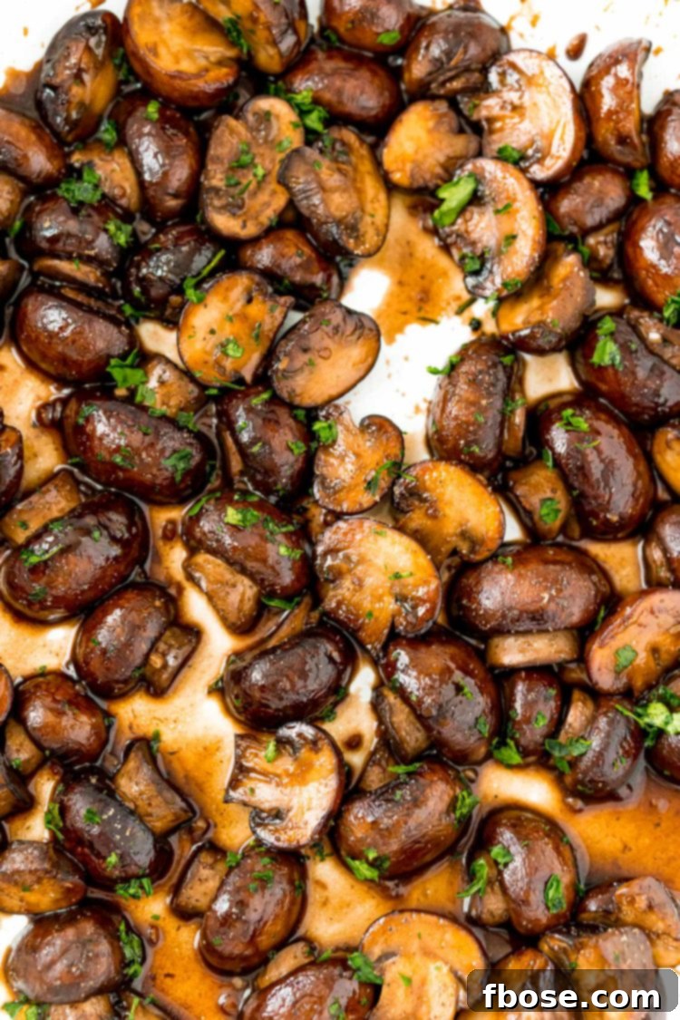 Overhead photo of beautifully cooked sauteed mushrooms, glistening with glaze, in a rustic cast iron skillet.