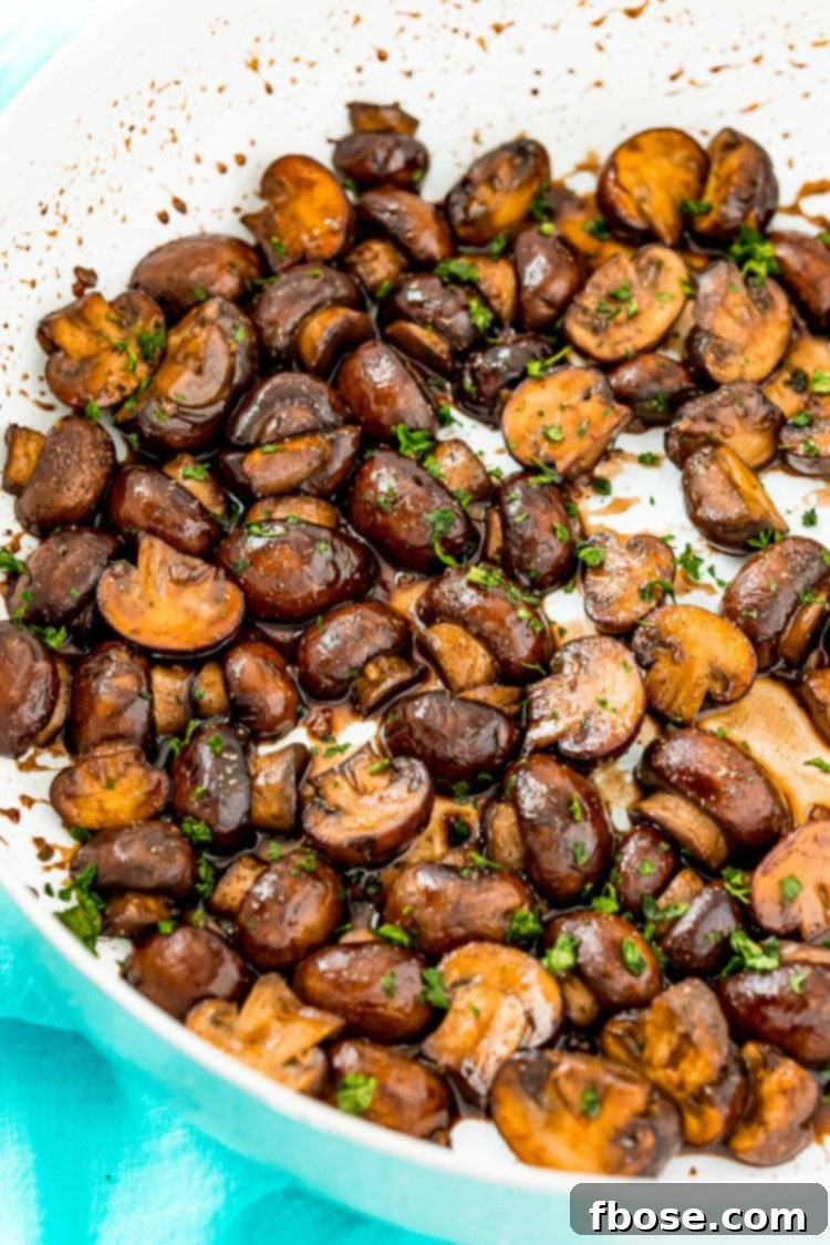 Sauteed mushrooms with balsamic glaze, garnished with fresh parsley in a rustic skillet.