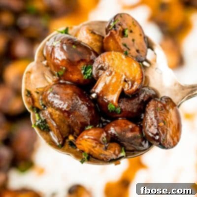 Serving spoon filled with sauteed mushrooms.