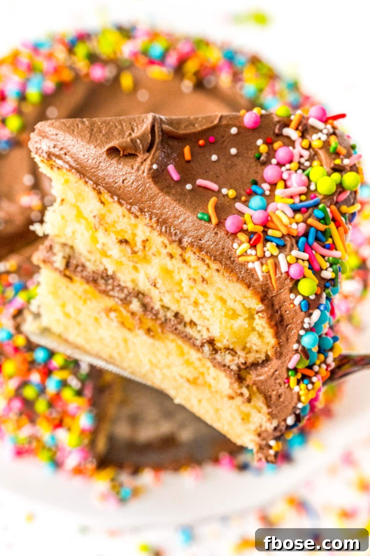 Slice of yellow layer cake being lifted with a cake server from the cake.