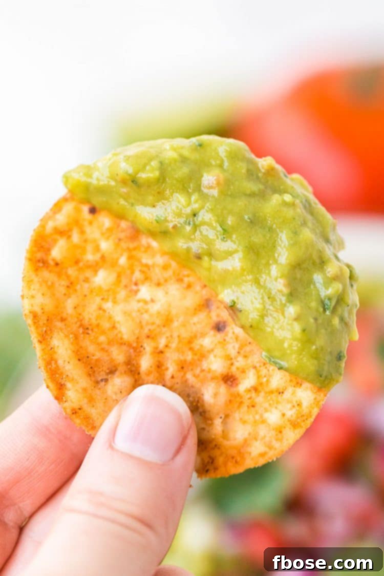 Guacamole 6 Woman's hand holding a tortilla chip that's been dipped in guacamole.