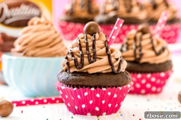 An inviting arrangement of chocolate cupcakes next to a small bowl of creamy malt frosting. In the soft-focused background, a classic jar of Ovaltine sits on the counter, hinting at the key ingredient.