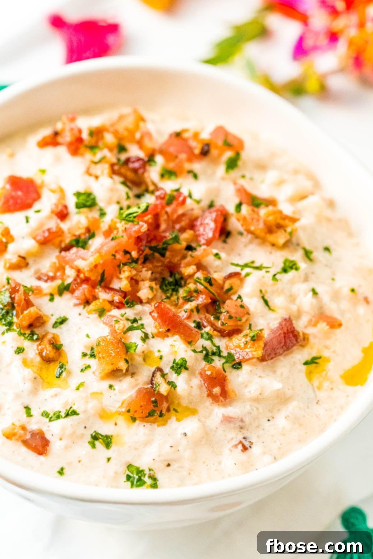 Close up photo of a bowl of creamy Bacon Cauliflower Chowder topped with crispy bacon bits and fresh herbs, perfect for a keto-friendly meal.