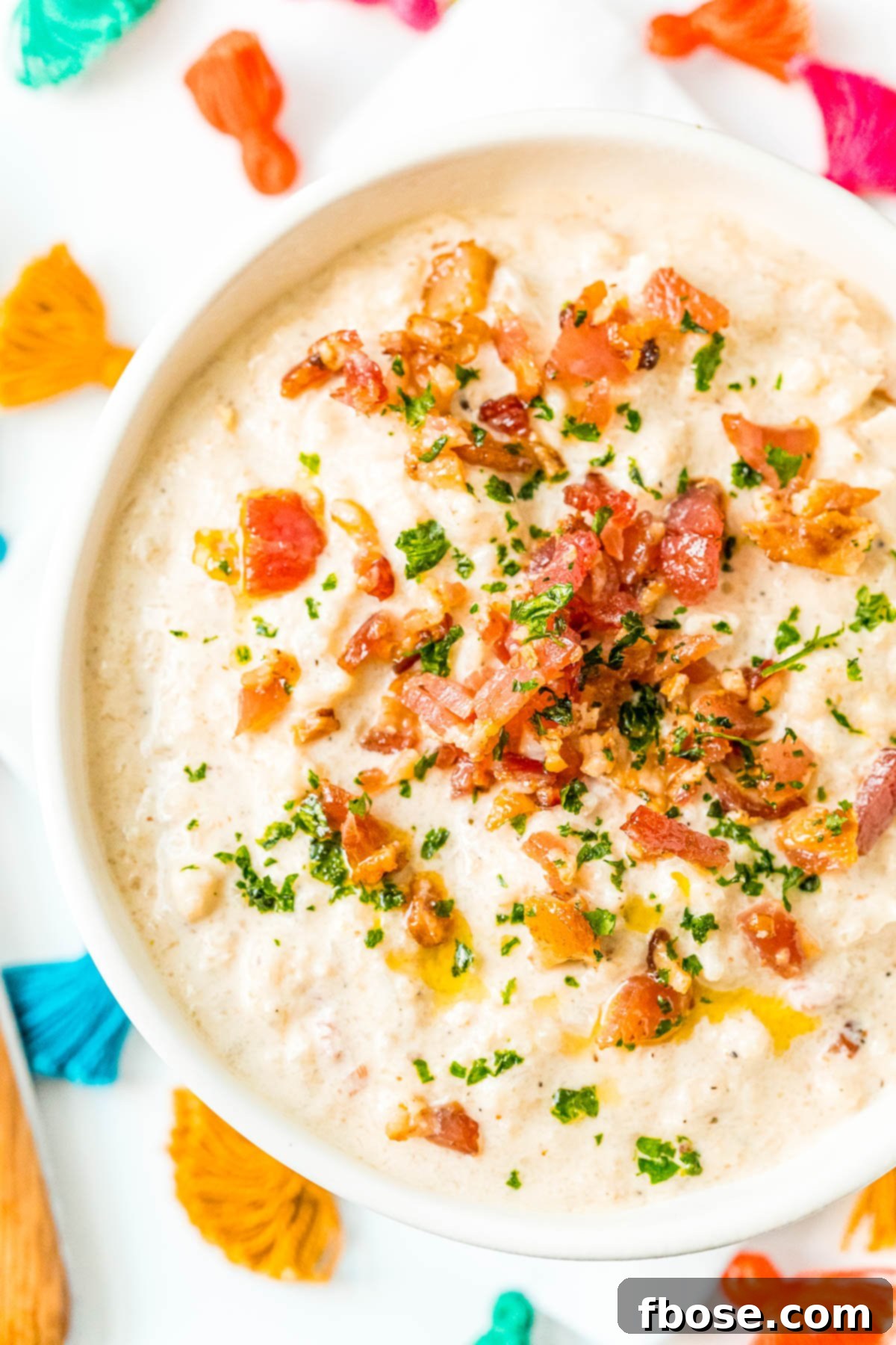 Overhead photo of a bowl of delicious Bacon Cauliflower Chowder garnished with fresh parsley and extra crispy bacon.