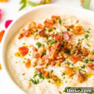 Close up photo of creamy cauliflower chowder with crispy bacon topping, highlighting its delicious texture and garnishes.