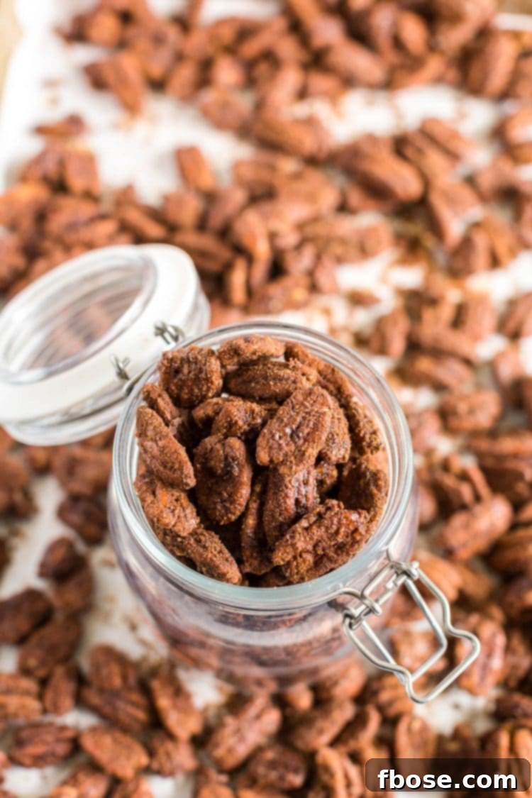 Candied pecans in a glass jar, showcasing their gift potential, with loose pecans scattered around.