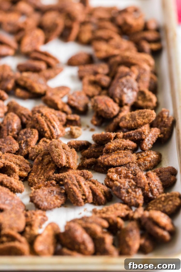 Candied pecans scattered evenly on a baking pan, ready to bake.