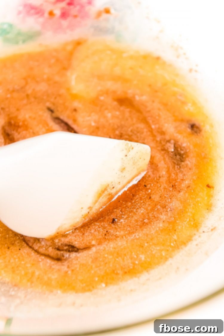 Melted butter and spices being stirred together in a glass bowl.