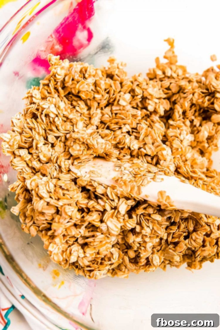 Oats being mixed with melted butter and spices in a glass bowl.