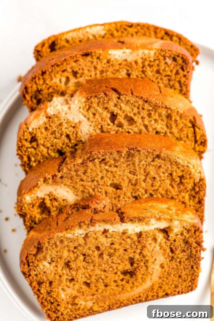 Delightful slices of pumpkin cream cheese bread, showcasing the golden pumpkin batter and creamy caramel swirl, presented on an elegant white plate.