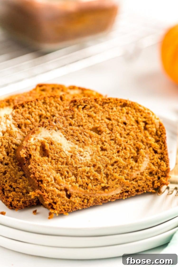 A close-up view of two inviting slices of pumpkin bread featuring a distinct cream cheese swirl, neatly arranged on a white plate, highlighting the delicious texture and layers.