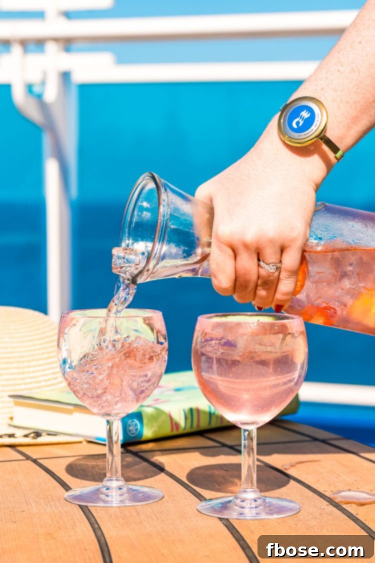 Woman pouring a cocktail out of a carafe into wine glasses on the deck of a cruise ship.