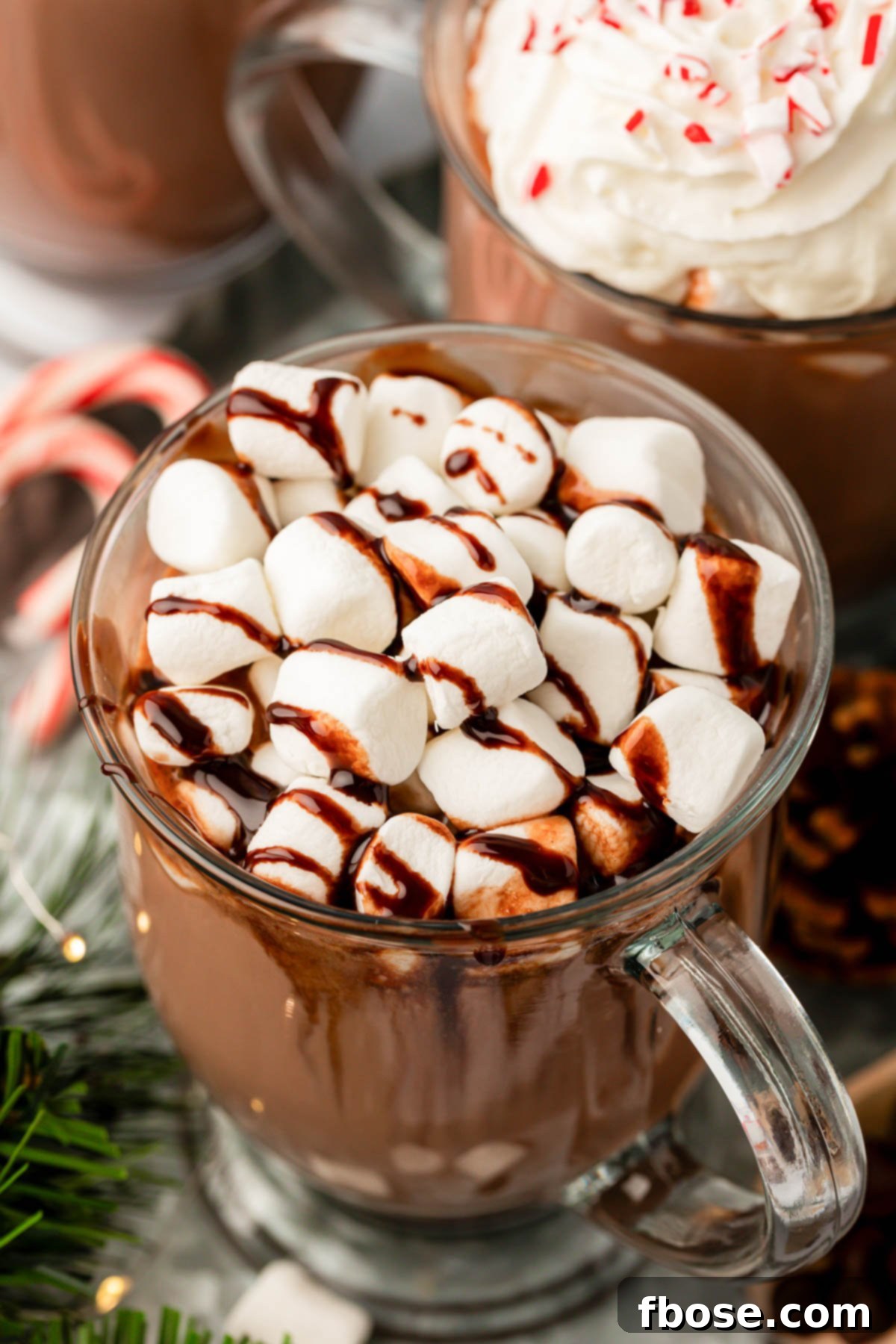 A close-up view of a mug brimming with rich, creamy crockpot hot chocolate, garnished with melted marshmallows, suggesting warmth and indulgence.