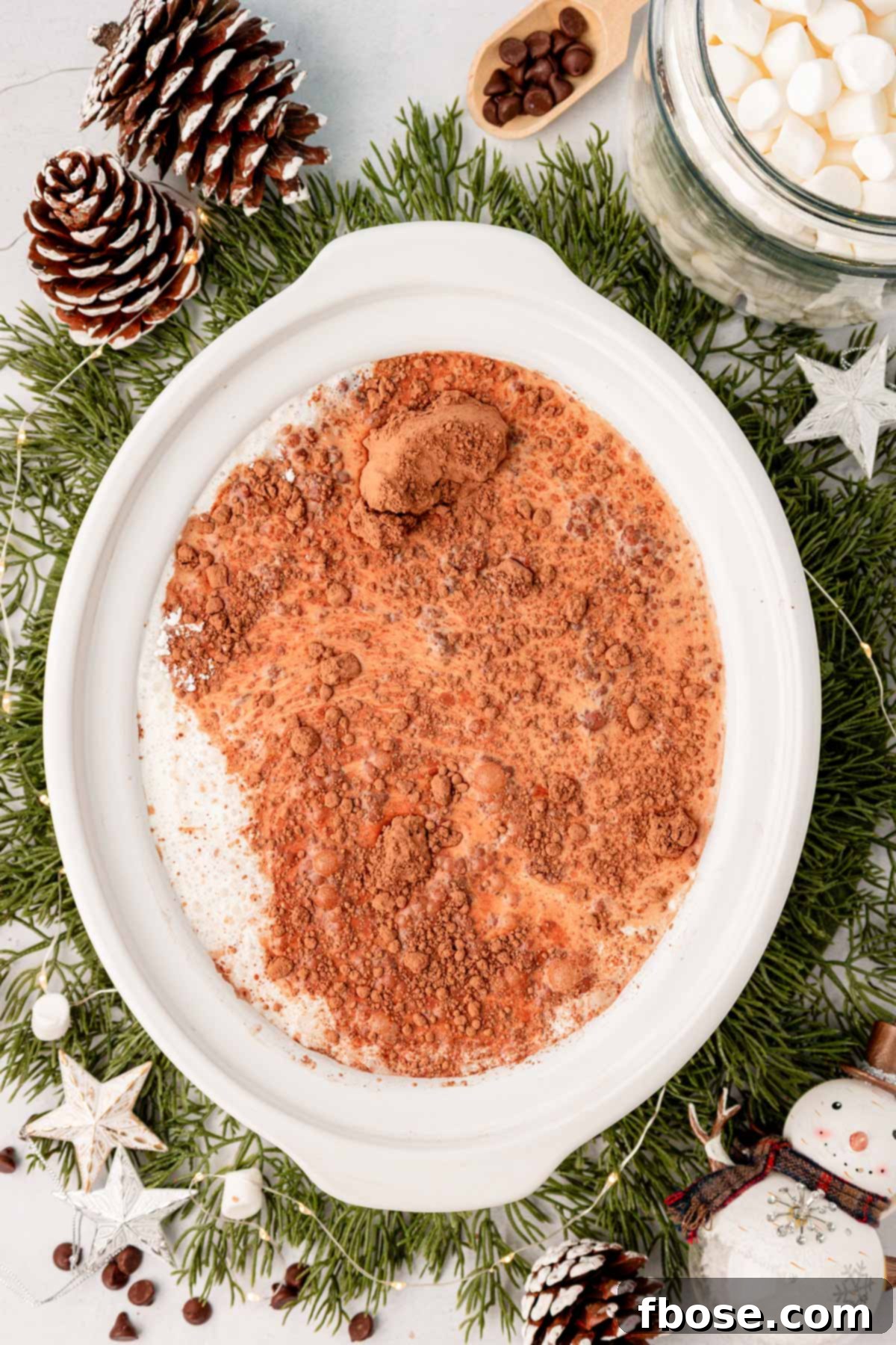 An overhead shot showing the process of making hot chocolate in a slow cooker, with ingredients being stirred together.