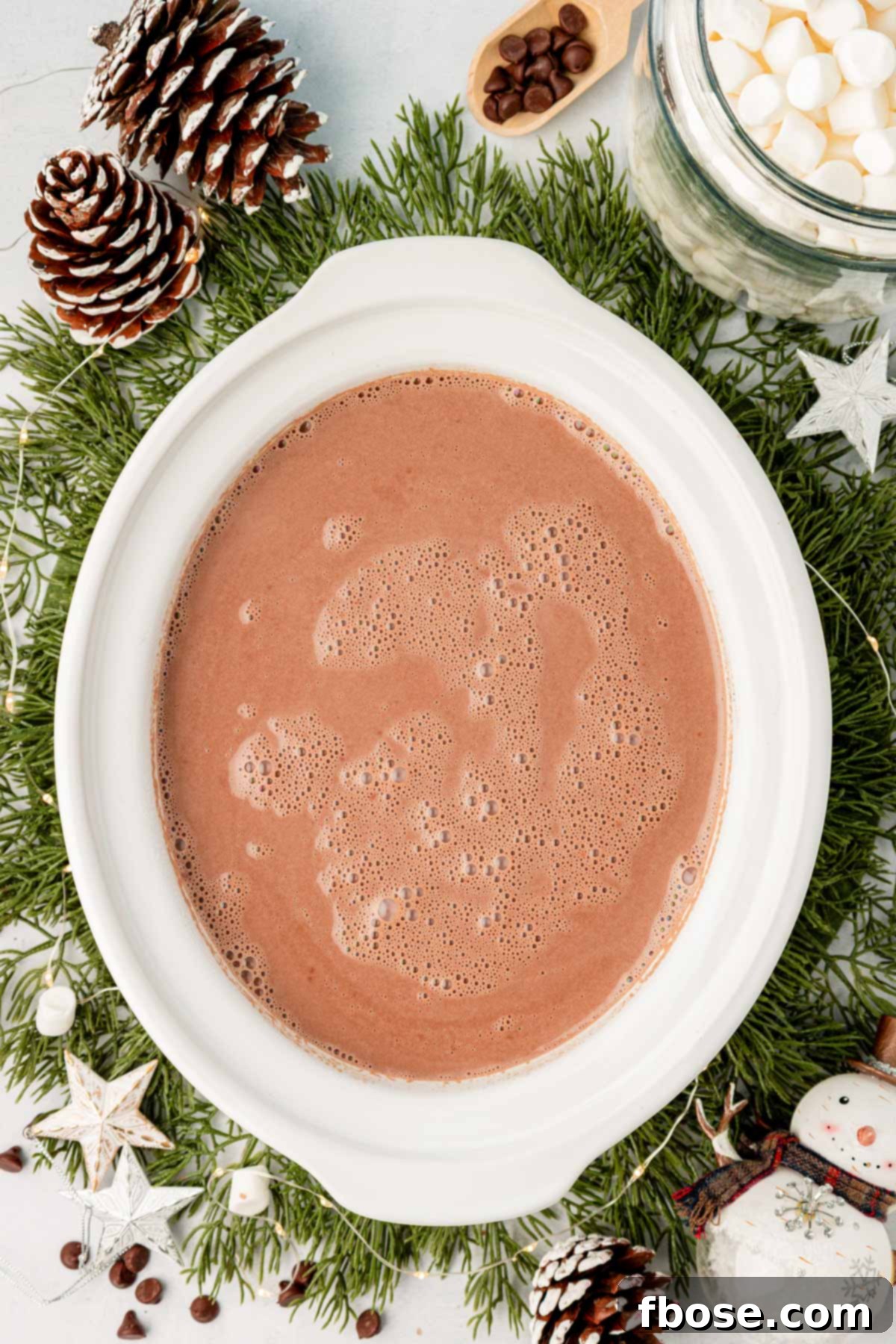 A pristine white crockpot filled with steaming, rich hot chocolate, ready for the next step.