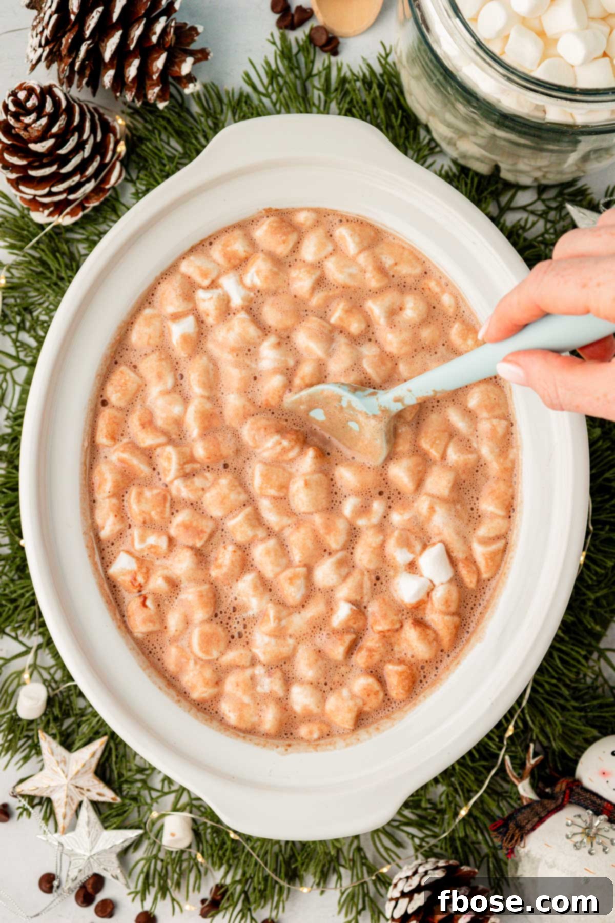 A mesmerizing view of the surface of a slow cooker filled with hot chocolate, completely covered by a thick, inviting layer of melted marshmallows.