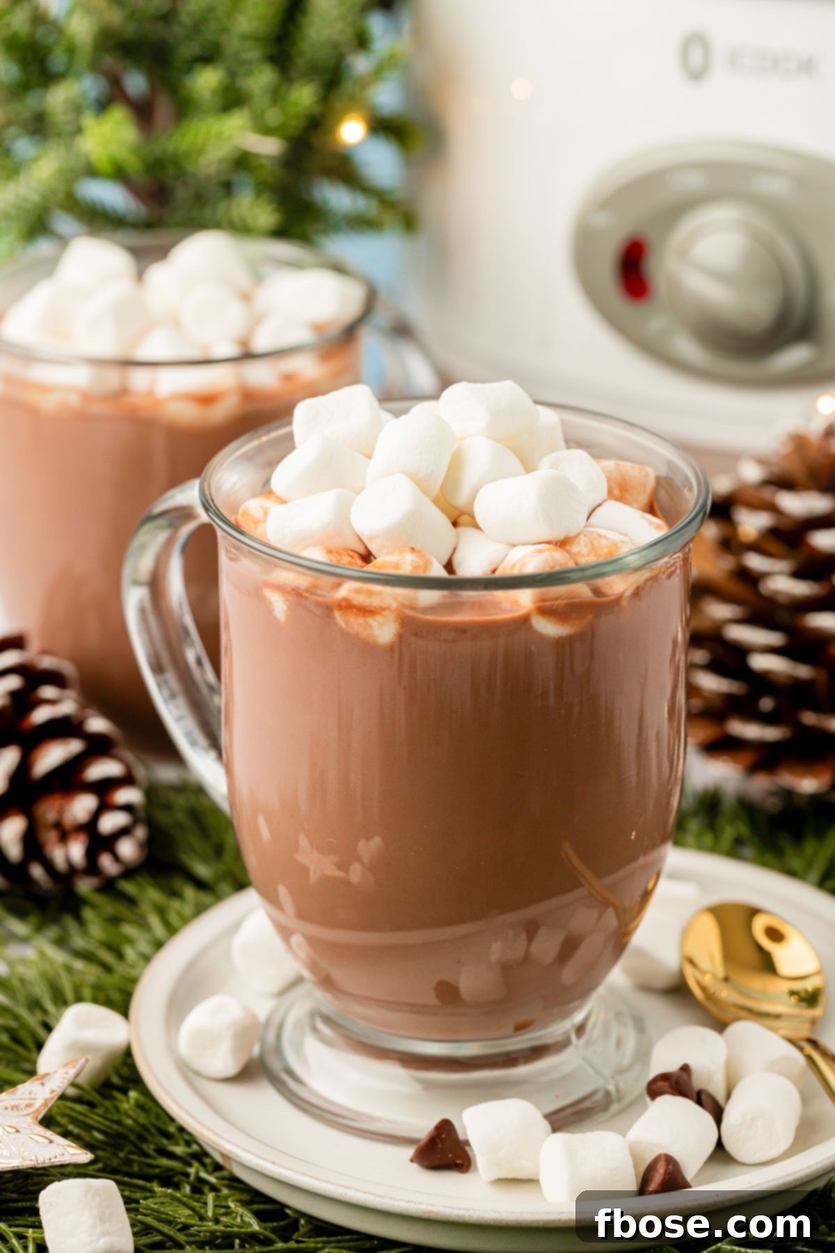 Two cozy mugs of hot chocolate placed in front of a slow cooker filled with the creamy beverage, inviting comfort and sharing.
