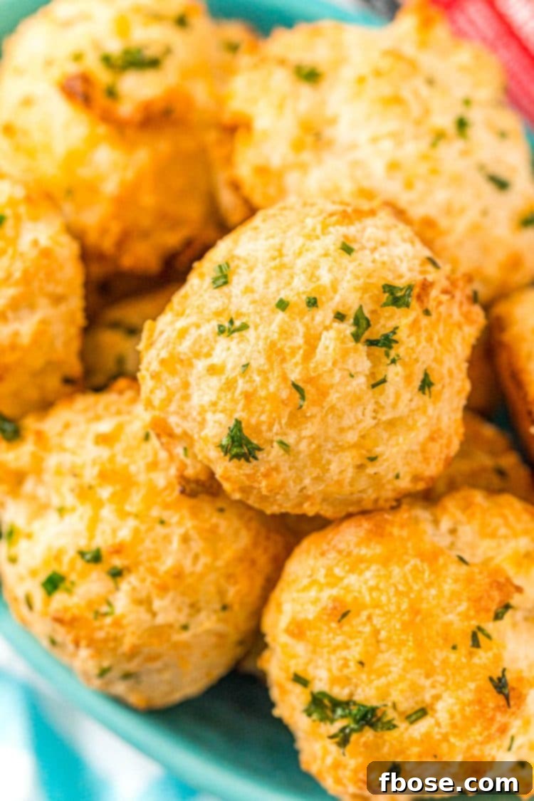 Close up photo of a bowl of cheddar drop biscuits topped with herbs.