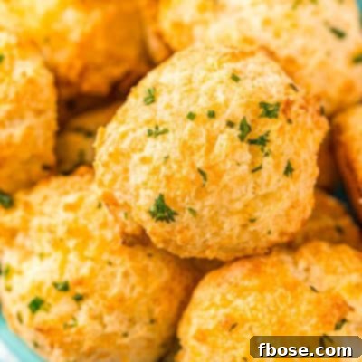 Close up photo of a bowl of cheddar drop biscuits topped with herbs.