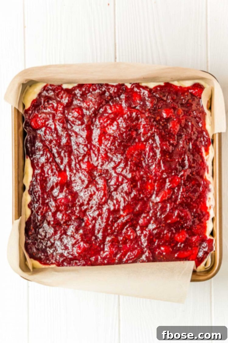 Cranberry filling on top of cheesecake filling in a square baking dish.