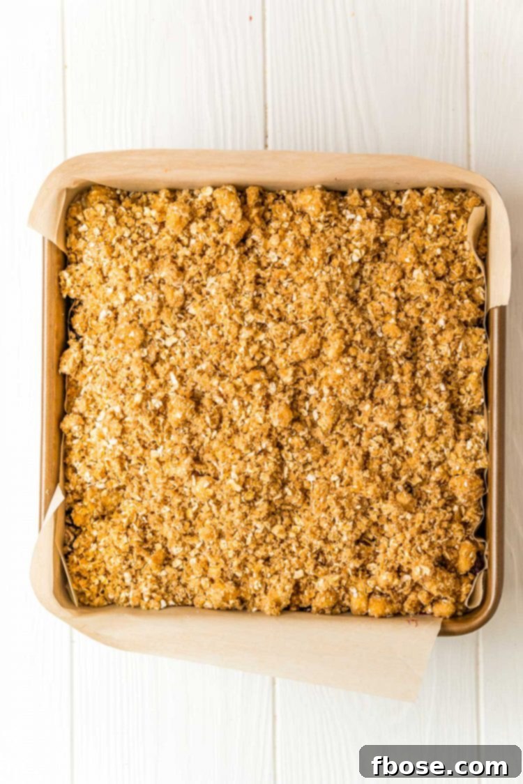 Oatmeal crumble topping on top of a cheesecake in a square baking dish.