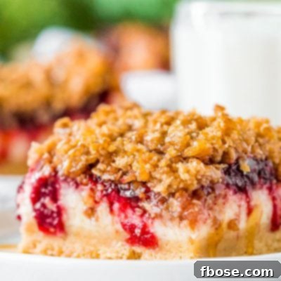 Close up photo of a slice of cranberry cheesecake bars on a small white plate.