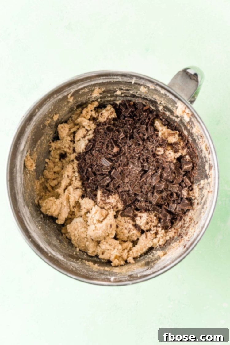Overhead photo of a mixing bowl filled with cookie dough and chocolate chunks ready to be mixed in.