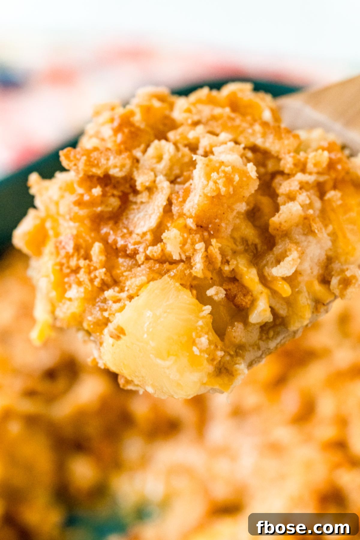 Close up photo of pineapple casserole scooped on a wooden spoon.