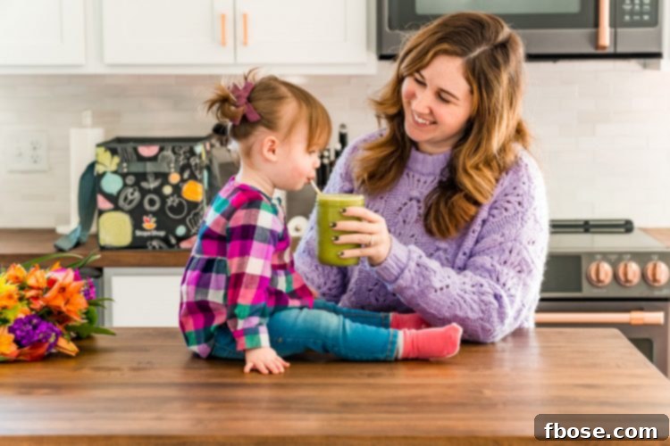 Mother and daughter in a kitchen drinking a smoothie.