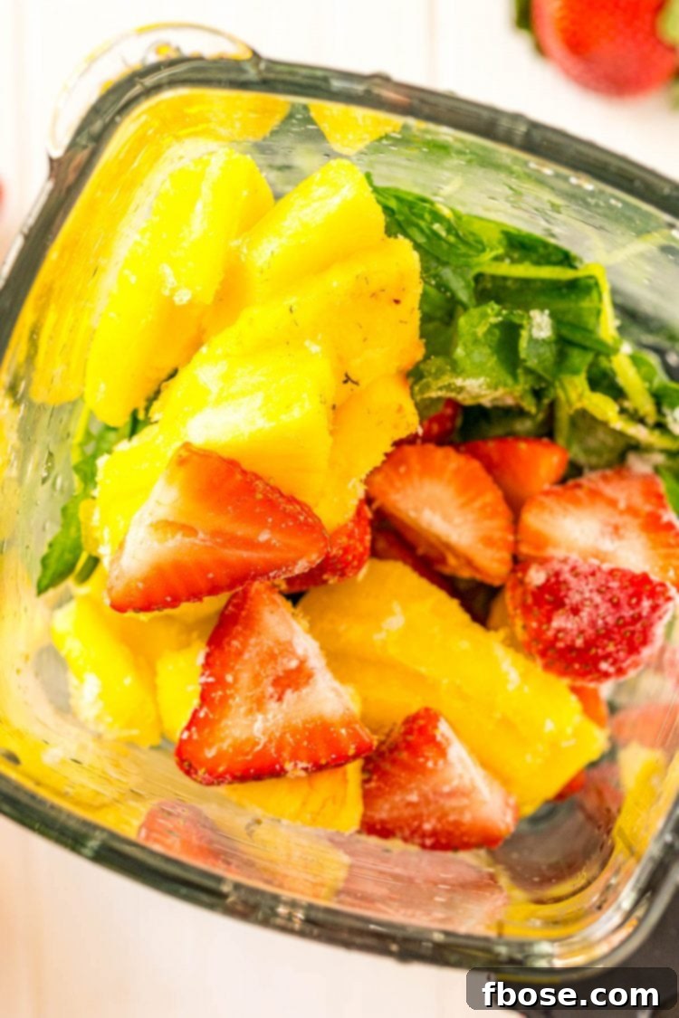 Overhead photo looking into a blender filled with frozen fruits and vegetables.