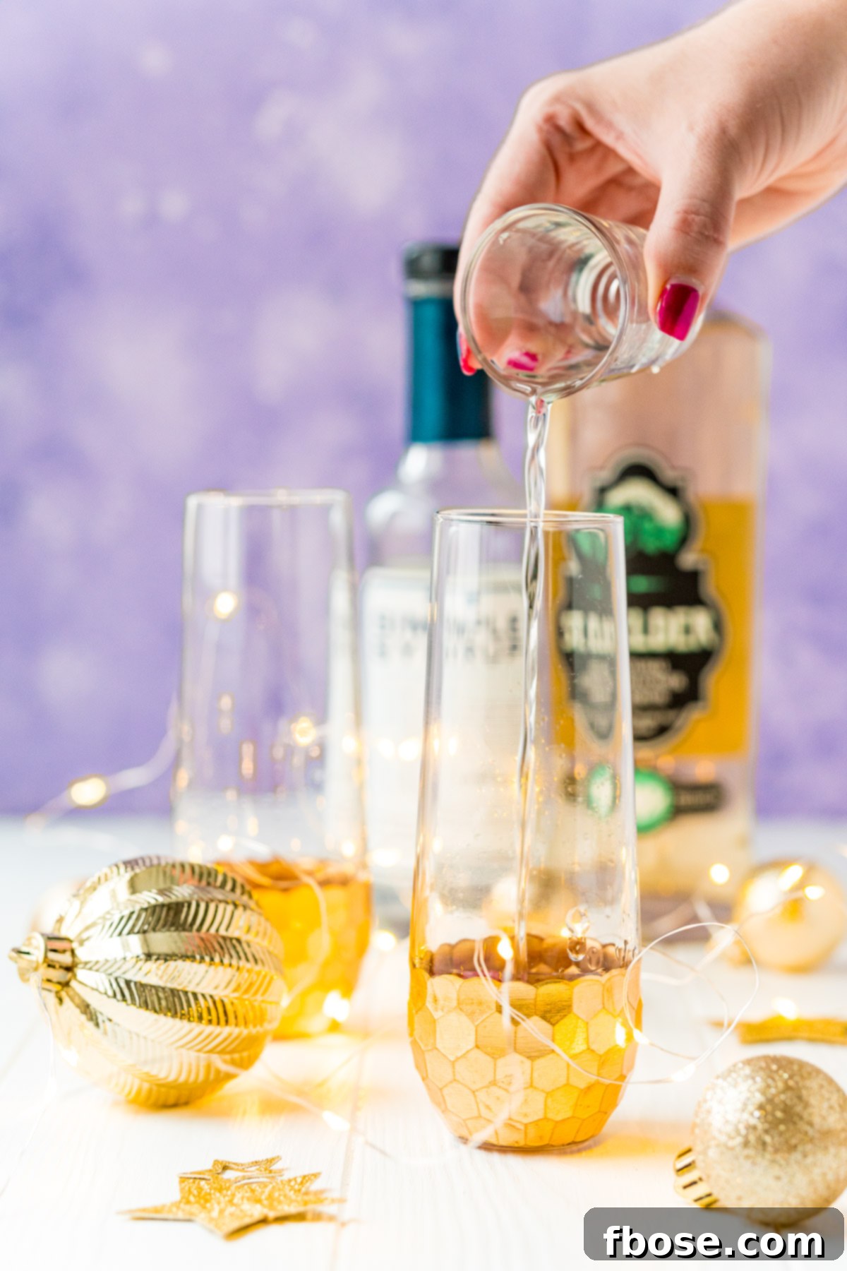 Golden Bloom Fizz 4 Woman's hand pouring liquor into a champagne flute.