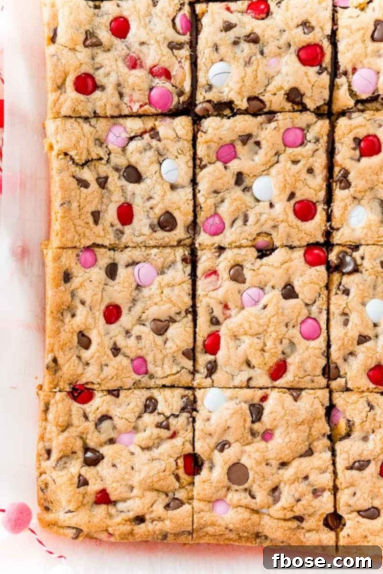 An overhead view of a fresh batch of chocolate chip cookie bars, perfectly sliced into squares and arranged on parchment paper, ready to be enjoyed.