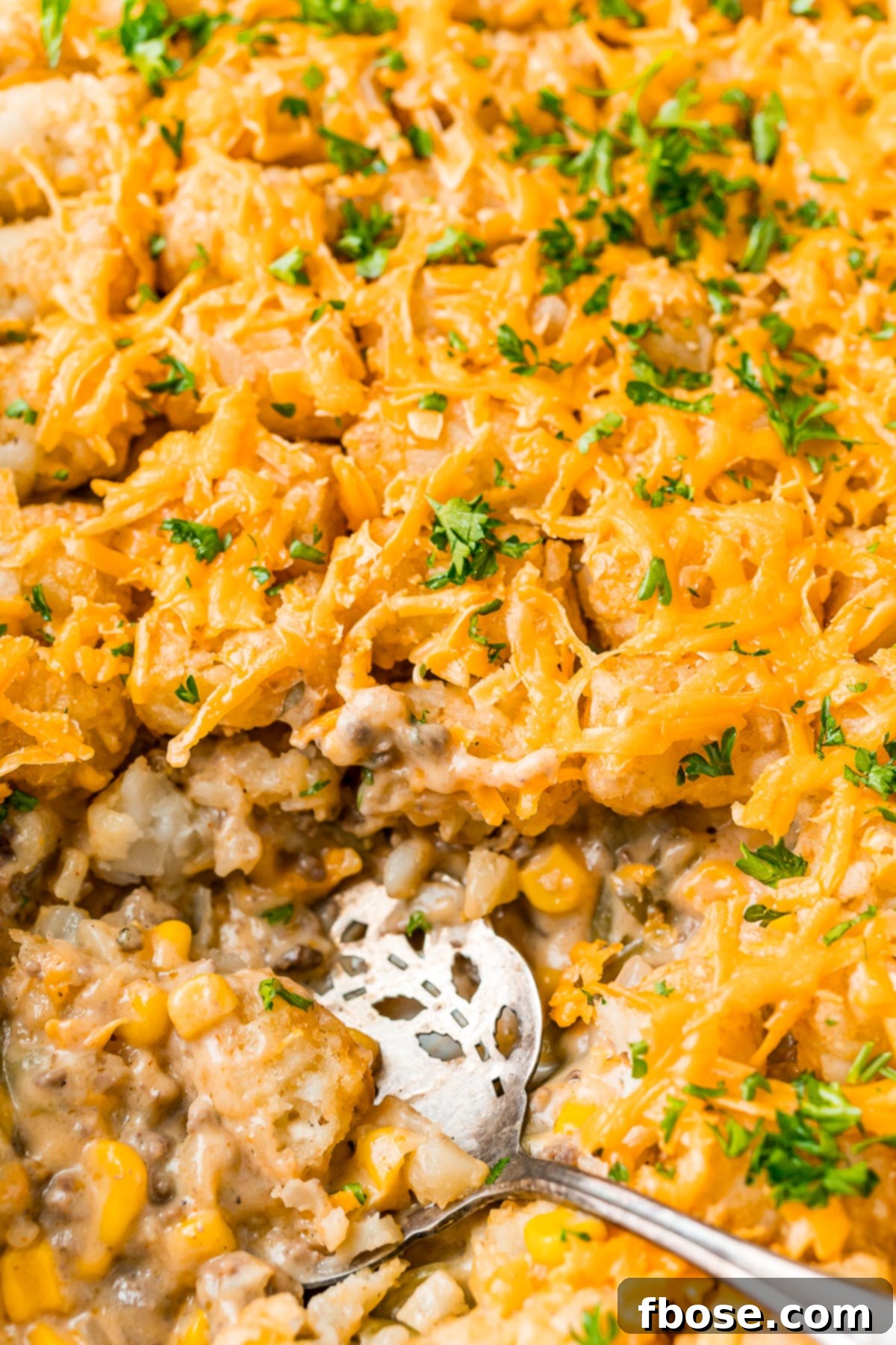 Close up overhead photo of a tater tot hot dish with a serving spoon resting in it.