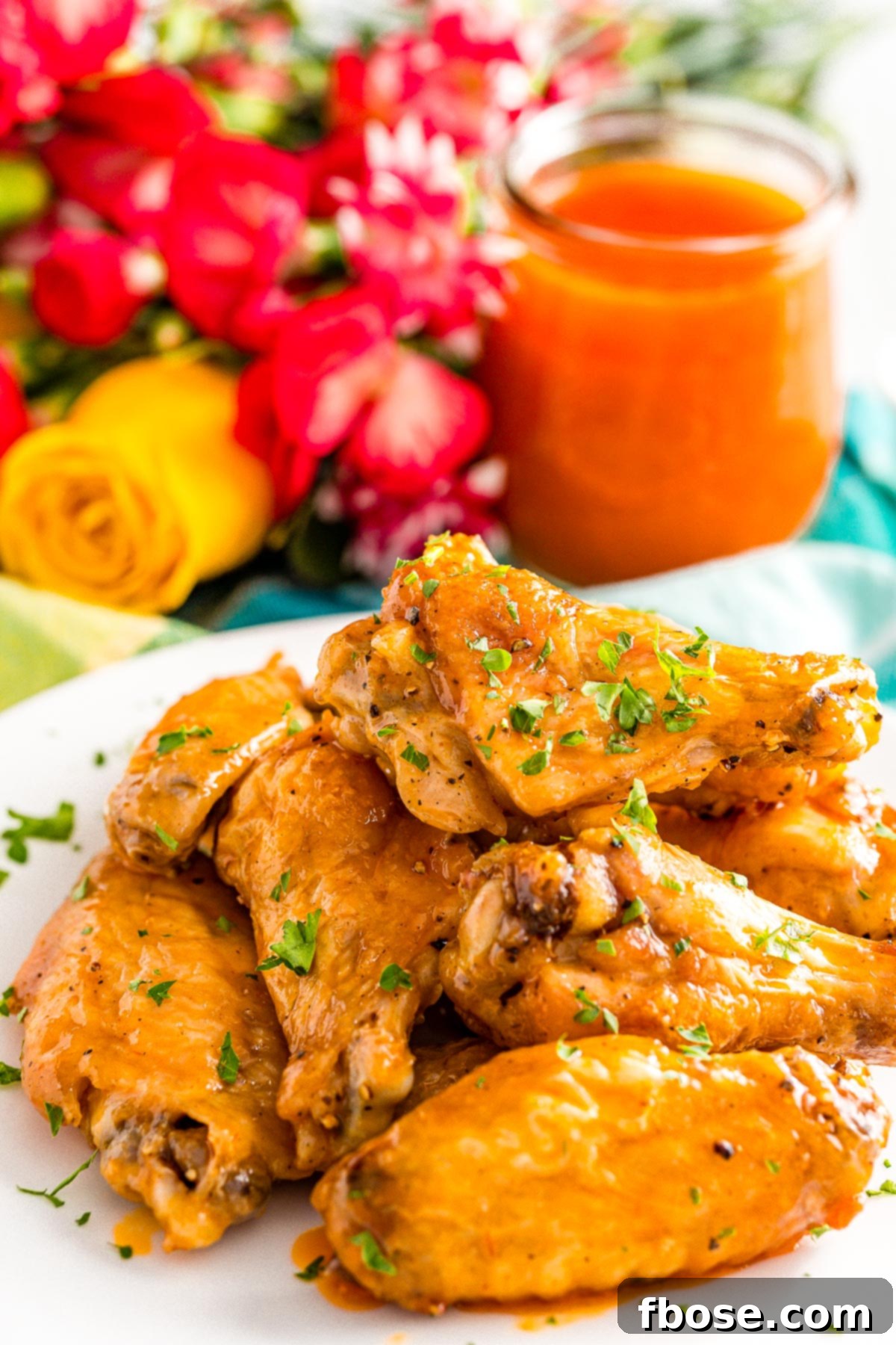 Crispy Oven Baked Wings 3 Crispy baked chicken wings on a white plate, with a bowl of vibrant buffalo sauce in the background, ready for dipping.
