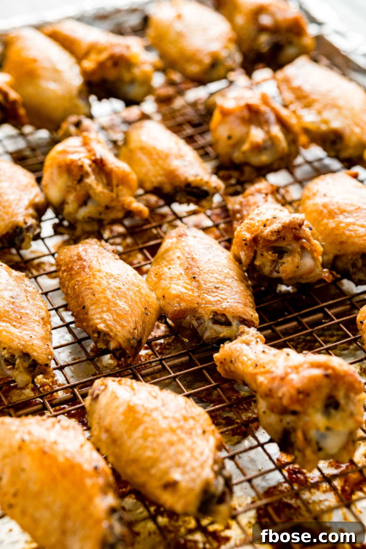 Crispy Oven Baked Wings 6 Freshly baked chicken wings, golden and crispy, cooling on a wire rack set over a baking sheet, straight out of the oven.