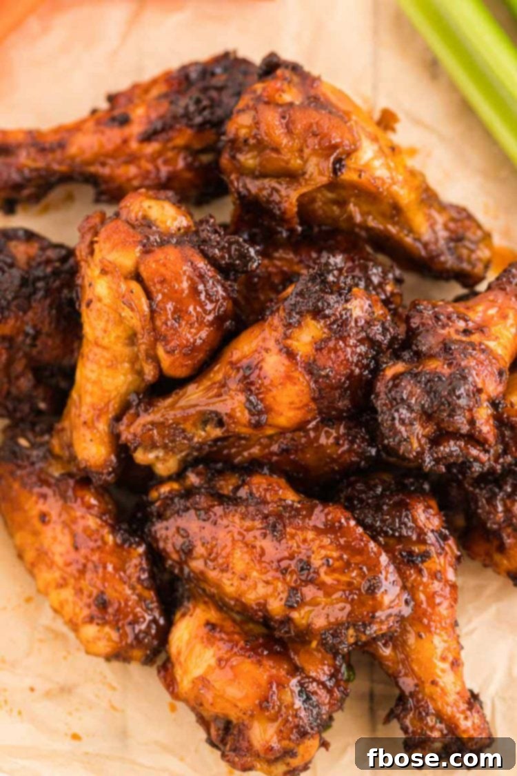 Chicken wings on a piece of parchment paper covered in a sticky hot sauce.