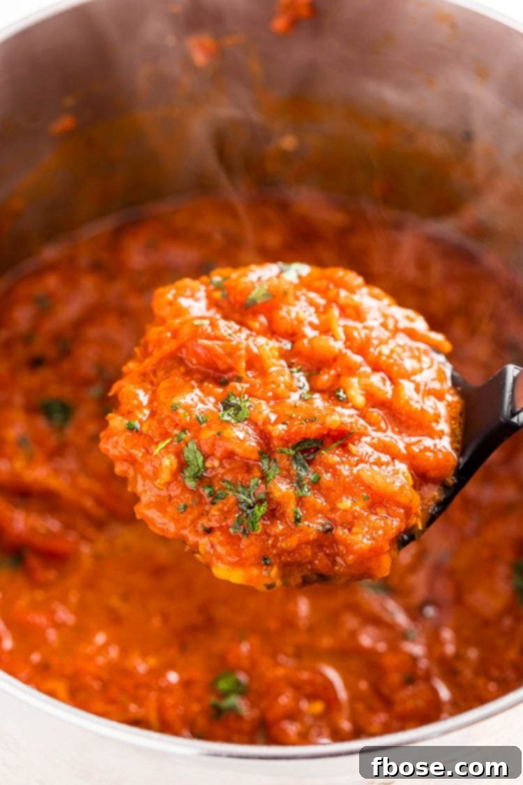 Signature Marinara 7 A ladle lifting a scoop of homemade marinara sauce out of a pot.