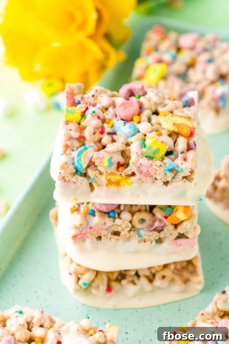 Three lucky charms treats stacked on top of each other on a blue cookie sheet.