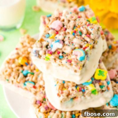 Lucky Charms Treats arranged on a white plate with a glass of milk and daffodils in the background.