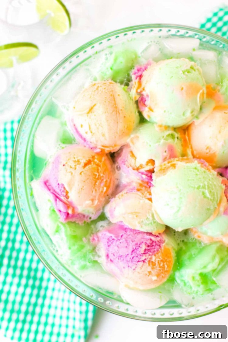 Whimsical Rainbow Sherbet Punch 3 Overhead photo of a bowl of punch topped with colorful rainbow sherbet, garnished with lime slices.