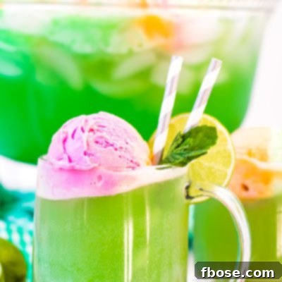 Close up photo of a clear mug filling with green punch.