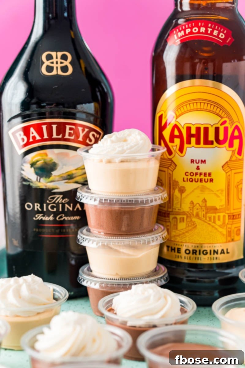 Stack of creamy pudding shots between a bottle of Baileys and a bottle of Kahlua, ready for an adult party.